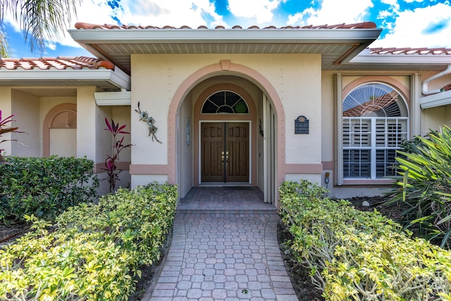 doorway to property with a tiled roof and stucco siding