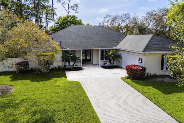 single story home featuring a shingled roof, an attached garage, decorative driveway, a front yard, and stucco siding