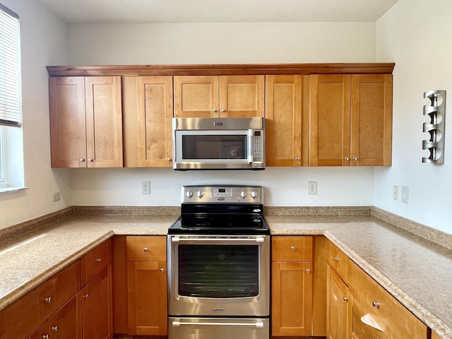 kitchen with appliances with stainless steel finishes, brown cabinets, and light countertops