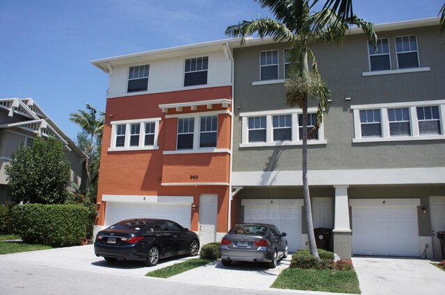 multi unit property featuring an attached garage, driveway, and stucco siding