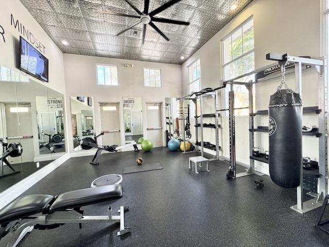 gym featuring a ceiling fan, a towering ceiling, visible vents, and a healthy amount of sunlight