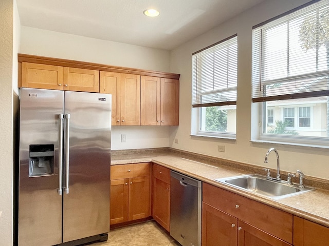 kitchen featuring appliances with stainless steel finishes, brown cabinets, light countertops, a sink, and recessed lighting