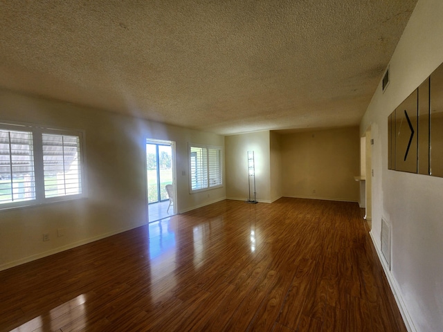 unfurnished room featuring baseboards, dark wood-type flooring, and a healthy amount of sunlight