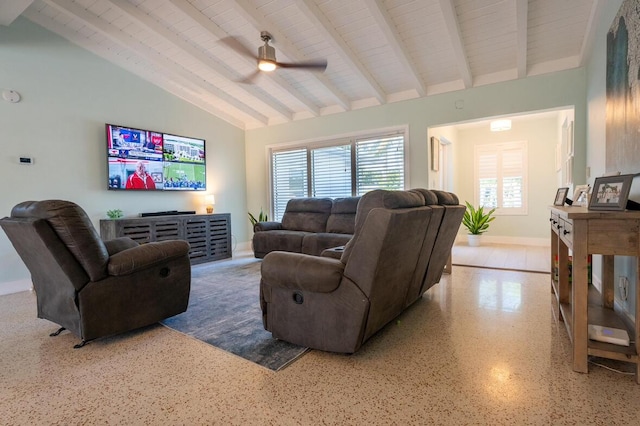 living room with speckled floor, baseboards, a ceiling fan, and vaulted ceiling with beams