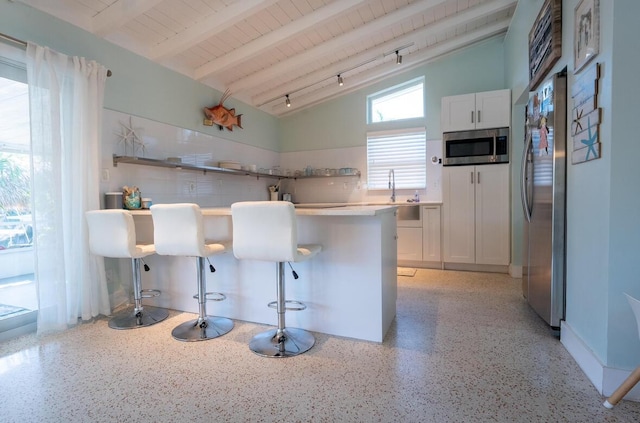 kitchen featuring open shelves, vaulted ceiling with beams, stainless steel appliances, white cabinets, and light speckled floor