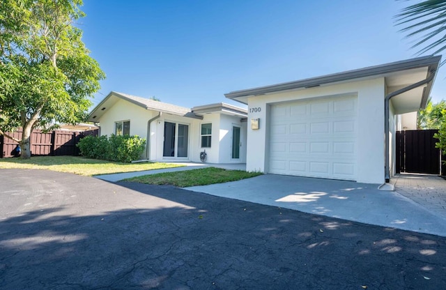 view of front of house with stucco siding, concrete driveway, an attached garage, and fence