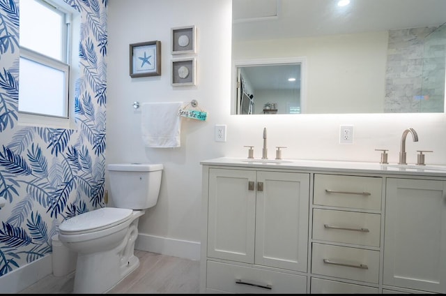 bathroom with double vanity, toilet, baseboards, and a sink