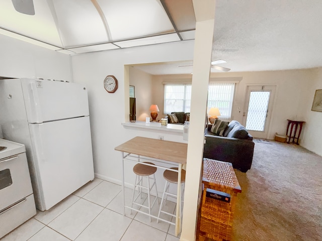 kitchen with white appliances, light colored carpet, open floor plan, and light tile patterned floors