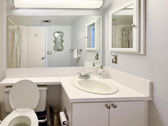 bathroom with curtained shower, vanity, and toilet