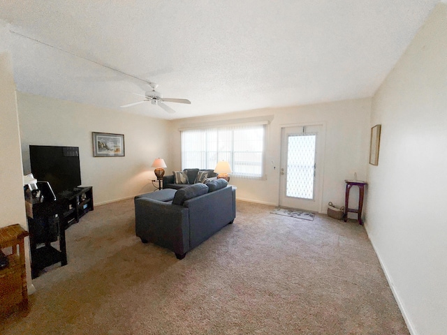 living room featuring carpet, ceiling fan, a textured ceiling, and baseboards