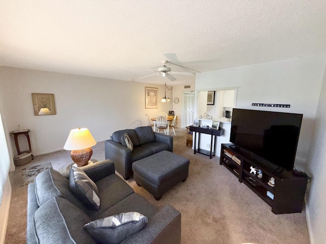 living area featuring a textured ceiling, ceiling fan, and light colored carpet