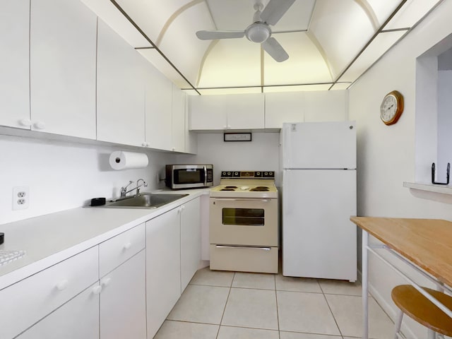 kitchen with white appliances, white cabinets, light countertops, a sink, and light tile patterned flooring