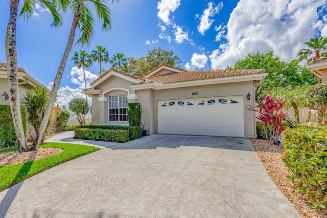 mediterranean / spanish-style house featuring concrete driveway, a tiled roof, an attached garage, and stucco siding