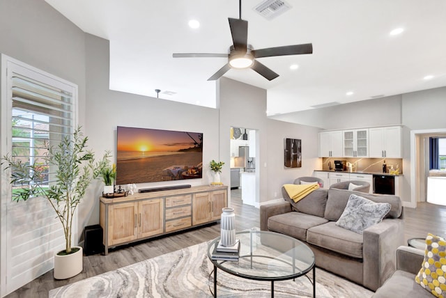 living room featuring a healthy amount of sunlight, light wood-type flooring, visible vents, and vaulted ceiling