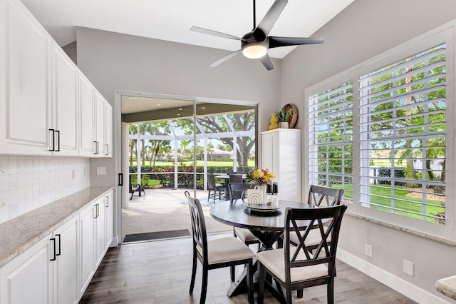 dining space with a sunroom, baseboards, dark wood finished floors, and a ceiling fan