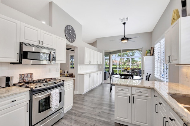 kitchen featuring stainless steel appliances, white cabinetry, visible vents, a wealth of natural light, and decorative backsplash