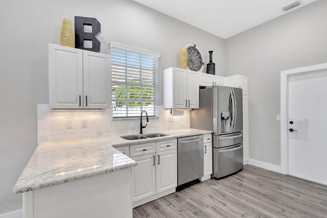 kitchen with stainless steel appliances, a sink, visible vents, light wood-style floors, and decorative backsplash