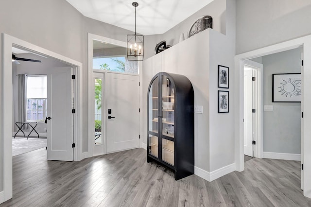 foyer featuring a towering ceiling, baseboards, a chandelier, and wood finished floors