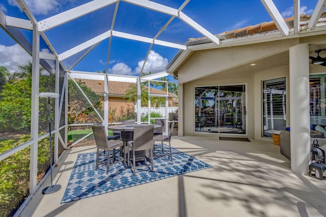 view of patio / terrace featuring a ceiling fan, outdoor dining area, and glass enclosure