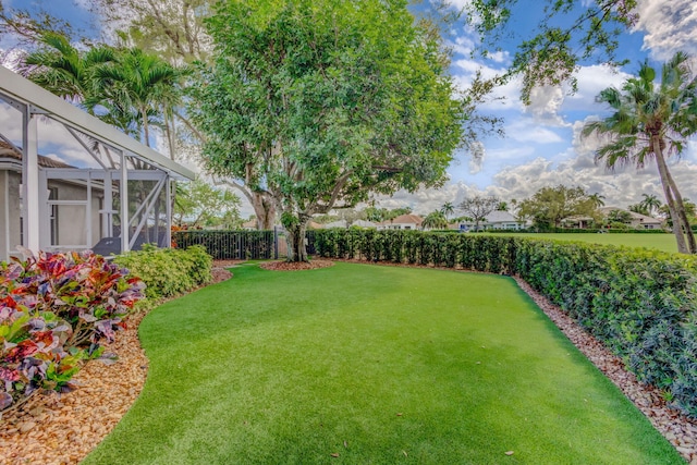 view of yard with glass enclosure and a fenced backyard