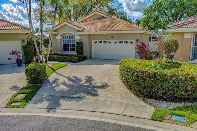 view of front of home featuring concrete driveway, a tile roof, an attached garage, and stucco siding