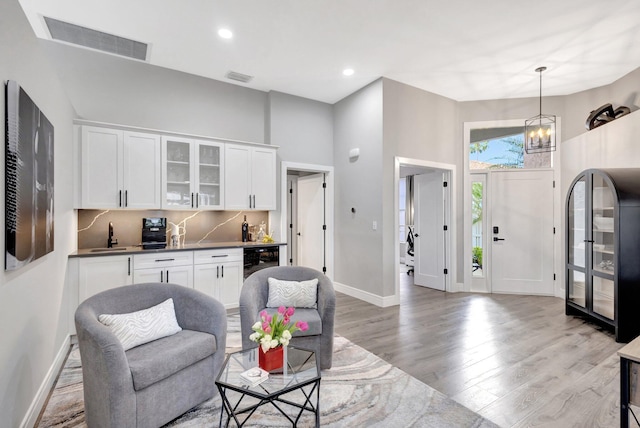 living area featuring light wood-style flooring, wine cooler, visible vents, and baseboards