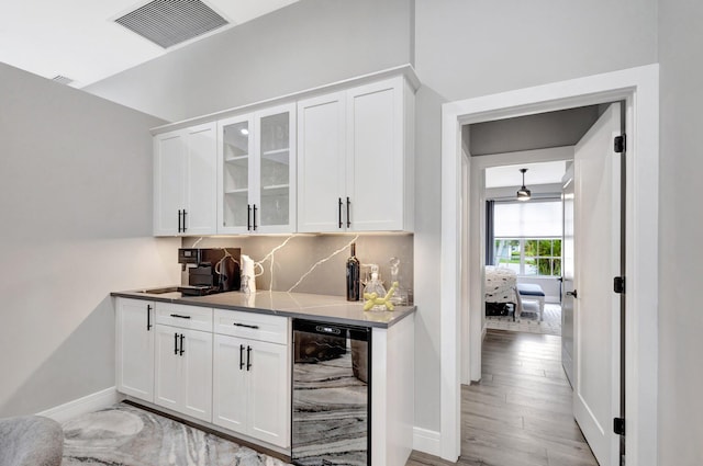 bar with wine cooler, visible vents, light wood-style flooring, backsplash, and baseboards