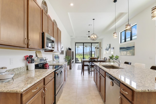 kitchen with appliances with stainless steel finishes, brown cabinetry, a sink, and light tile patterned floors