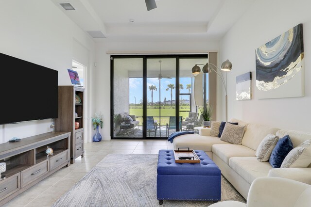 living room featuring light tile patterned floors, visible vents, and a tray ceiling