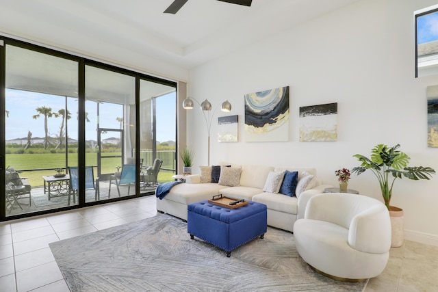 living area featuring ceiling fan, baseboards, and tile patterned floors