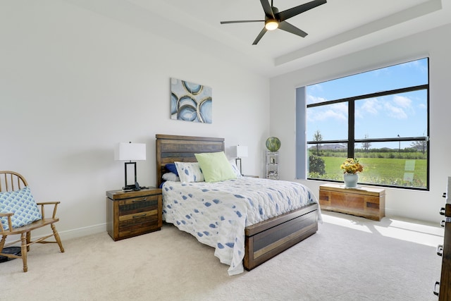 bedroom with a tray ceiling, carpet flooring, ceiling fan, and baseboards