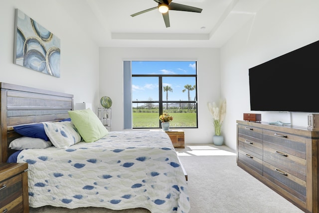 carpeted bedroom with a ceiling fan and a tray ceiling