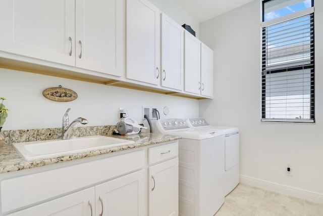 washroom with light tile patterned floors, cabinet space, washing machine and dryer, a sink, and baseboards