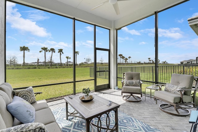 sunroom featuring a ceiling fan and a rural view