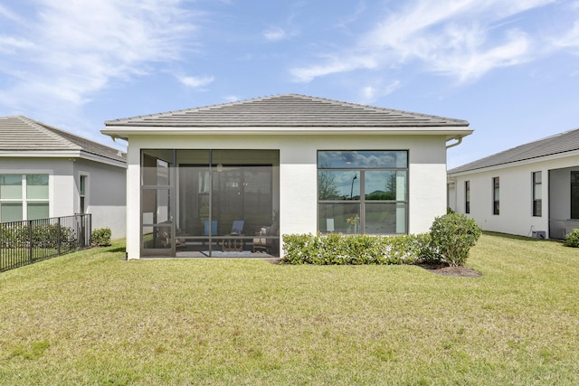 back of house featuring stucco siding, a lawn, a sunroom, fence, and a tiled roof