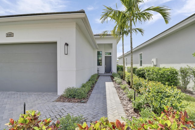 doorway to property with a garage and stucco siding