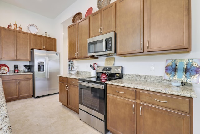 kitchen featuring light stone countertops, appliances with stainless steel finishes, and brown cabinets