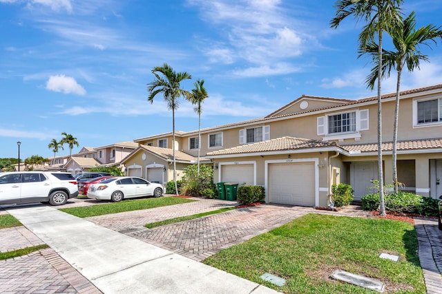 view of property featuring a garage, a residential view, a tiled roof, decorative driveway, and stucco siding