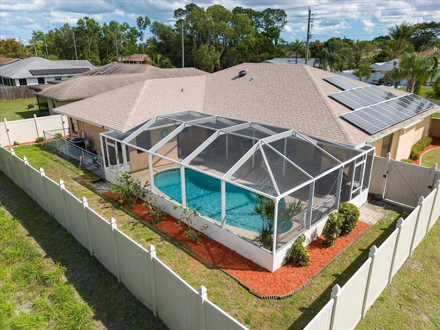 view of pool with a lanai, a gate, a fenced backyard, and a lawn