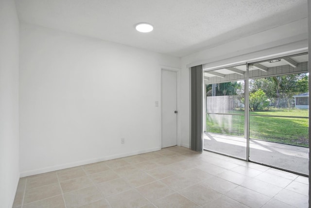 unfurnished room with light tile patterned floors, a textured ceiling, and baseboards