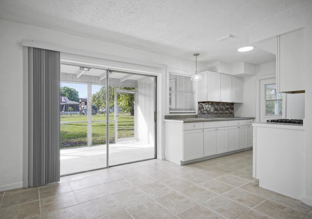 kitchen featuring a textured ceiling, white cabinetry, decorative backsplash, dark countertops, and decorative light fixtures