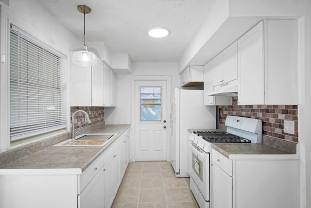 kitchen with decorative light fixtures, white gas stove, white cabinets, a sink, and under cabinet range hood