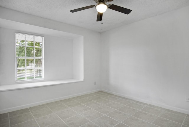 spare room with a textured ceiling, light tile patterned floors, and baseboards