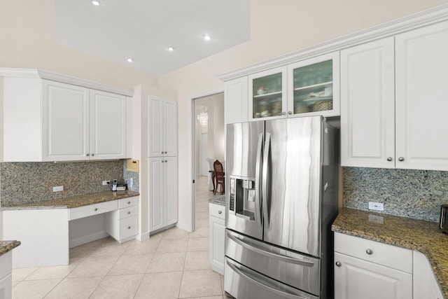 kitchen featuring dark stone countertops, stainless steel fridge, glass insert cabinets, and white cabinets