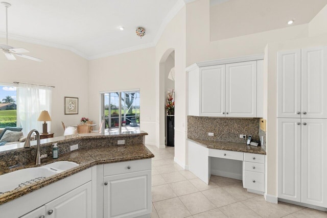 kitchen with ornamental molding, dark stone counters, white cabinetry, and a sink