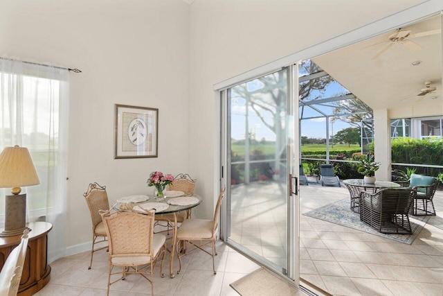 dining space with a sunroom, light tile patterned floors, a high ceiling, and a ceiling fan