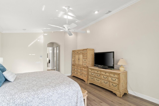 bedroom with baseboards, visible vents, arched walkways, ornamental molding, and wood finished floors