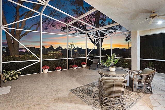 patio terrace at dusk with glass enclosure and a ceiling fan