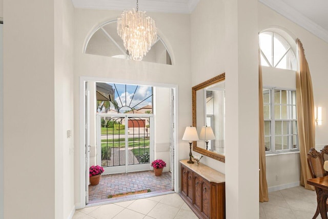 entryway featuring light tile patterned floors, a towering ceiling, an inviting chandelier, ornamental molding, and baseboards