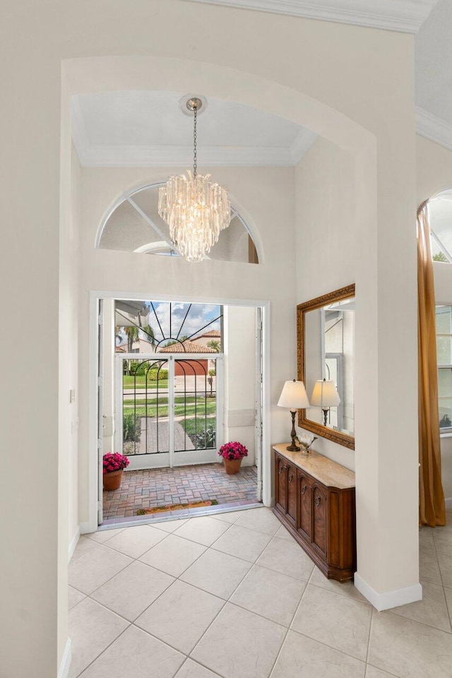 foyer featuring ornamental molding, arched walkways, a notable chandelier, and light tile patterned floors